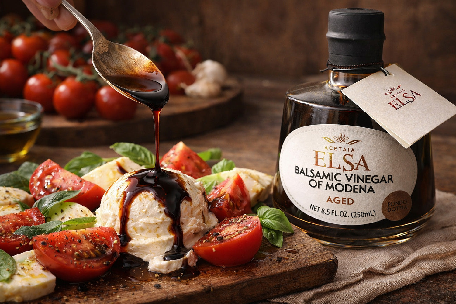 Aged Balsamic vinegar being drizzled over a salad with a bottle of Elsa Balsamic Vinegar of Modena in the background.