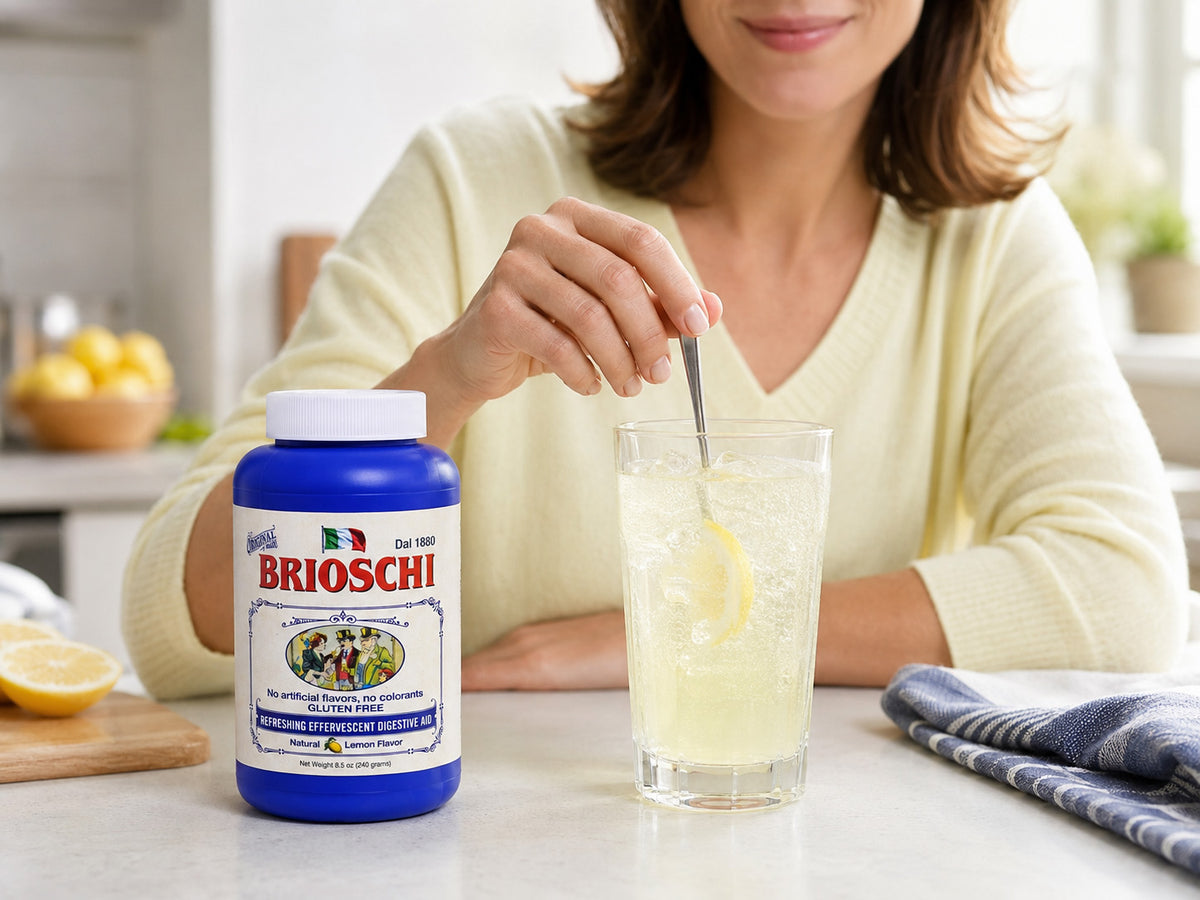Woman stirring a glass of Brioschi powder with lemons on a kitchen counter.