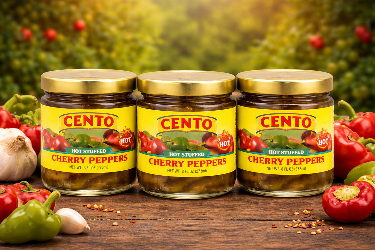 Three jars of Cento hot stuffed cherry peppers on a wooden surface with peppers and garlic in the background.