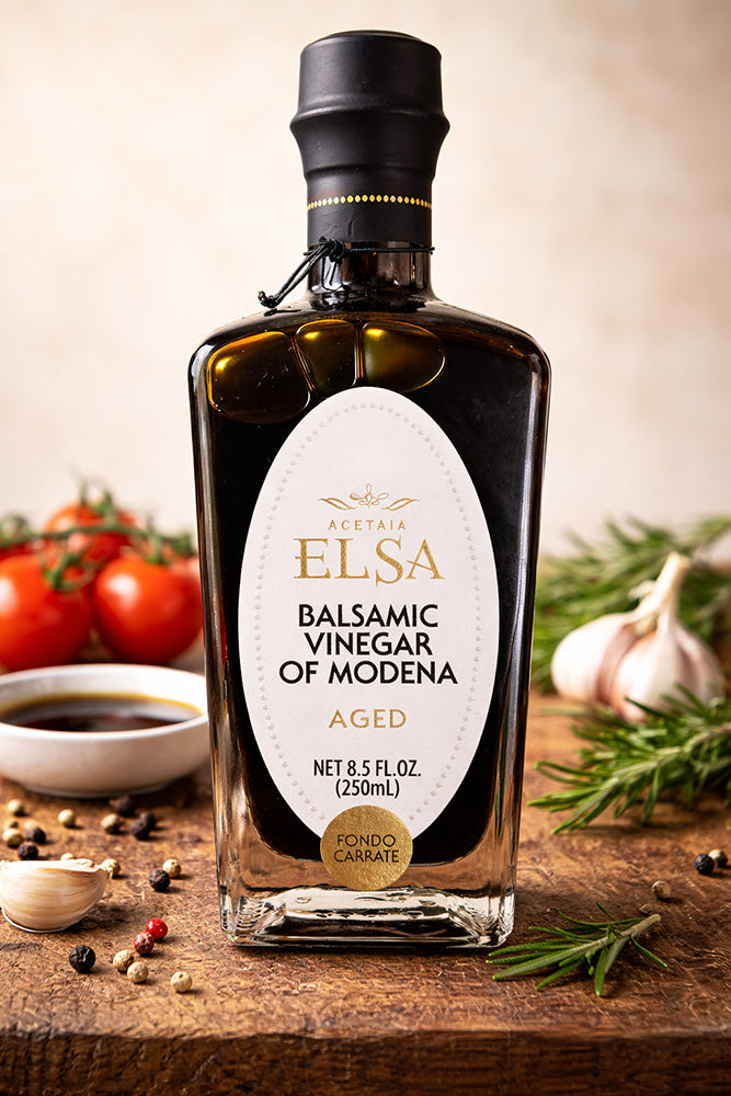 Bottle of Elsa Balsamic Vinegar of Modena on a wooden surface with ingredients in the background