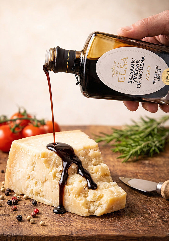 Elsa Balsamic vinegar being poured onto a block of cheese with tomatoes and rosemary