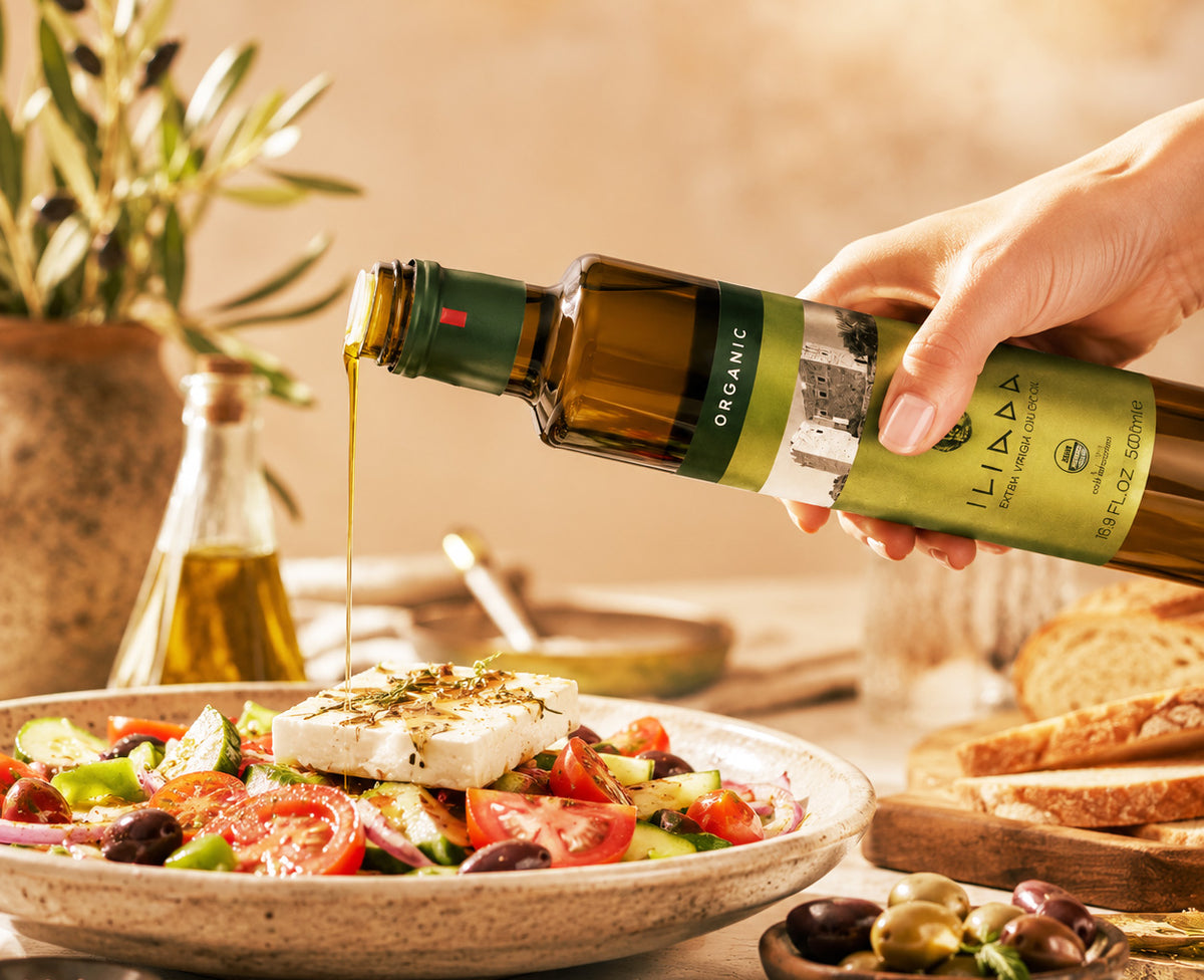 Iliada Olive Oil being poured over Mediterranean salad with feta cheese 