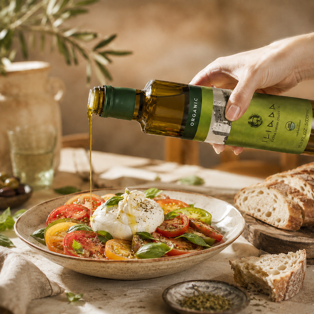 Iliada Olive Oil being poured over Mediterranean salad and heirloom tomato.
