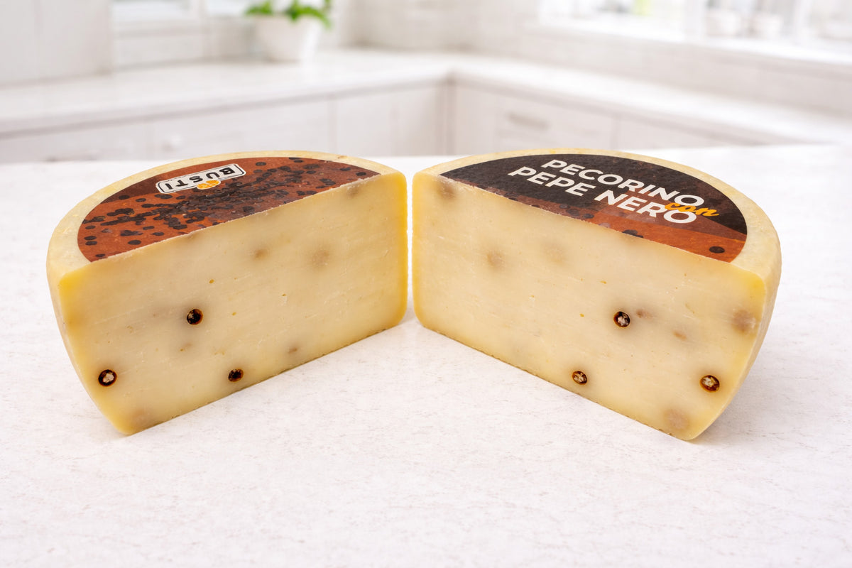 Two wedges of  Pepe Nero cheese on a white surface. Pecorino with Black peppercorn 