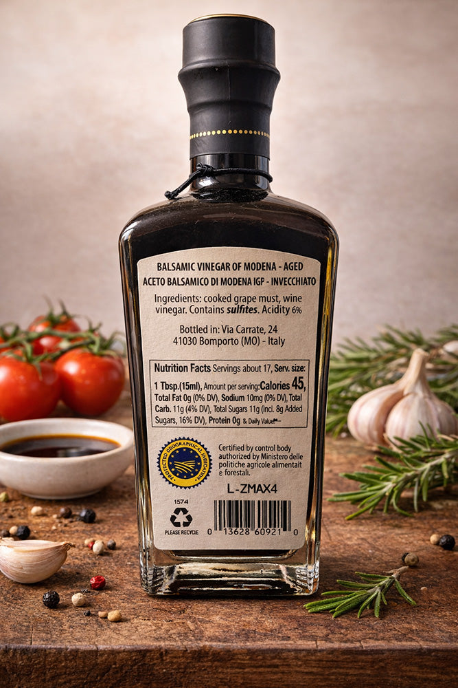 Elsa Bottle of balsamic vinegar with ingredients and nutrition facts label on a wooden surface with tomatoes and garlic in the background.