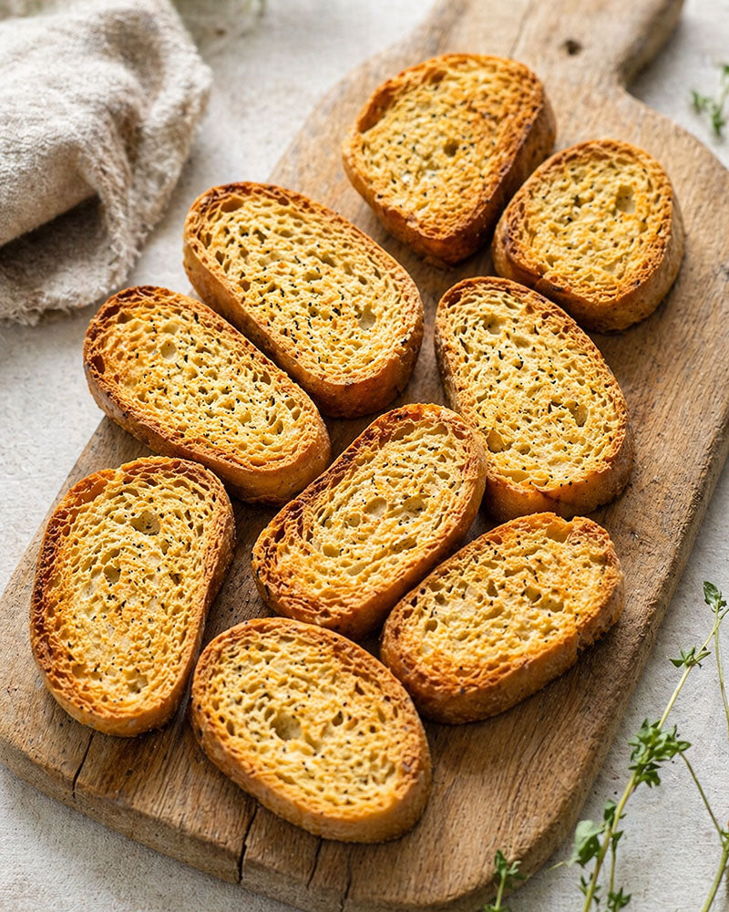 Slices of Frisella on a wooden cutting board with a light background