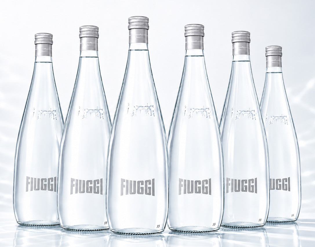 Six clear glass bottles of Fiuggi Water on a white background