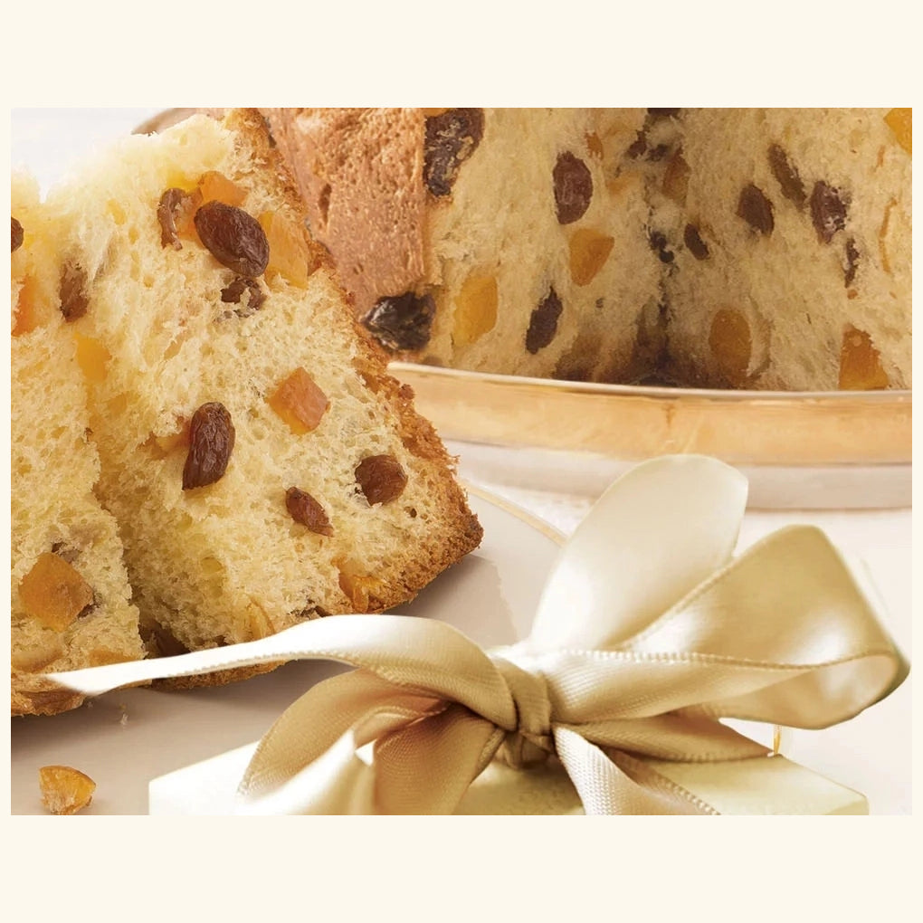 Bauli Panettone di Milano sliced to show raisins and candied citrus, beside a gold gift ribbon.