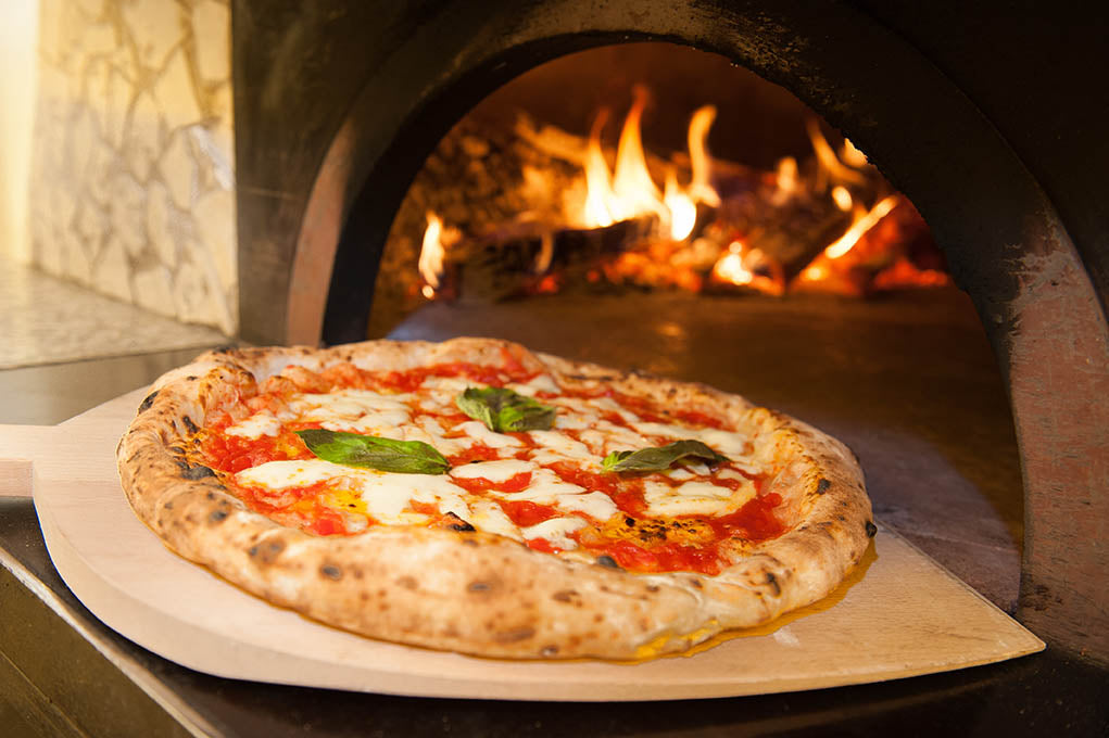 Margherita pizza in a wood-fired oven with flames visible Frank and Sal Pizza dough