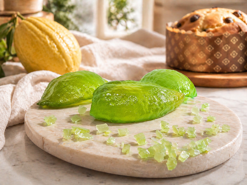 Whole Citron Pieces Next to a Panettone and Fresh Citron on a piece of white marble 